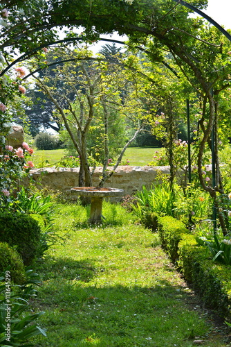 Roseraie avec table en pierre, jardin breton