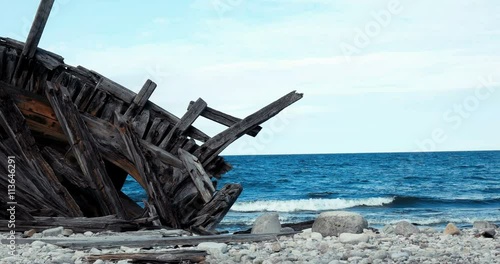 Detail of wrecked wooden ship on the coast against a calm sea photo