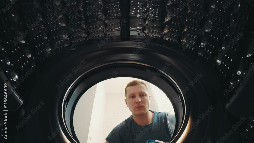 A man opens the door and load the laundry into the washing machine A man opens the door and load the laundry into the washing machine