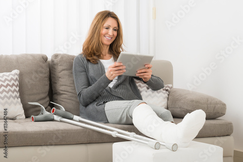 Leinwand Poster Frau mit Beinbruch mit digitalen Tablet