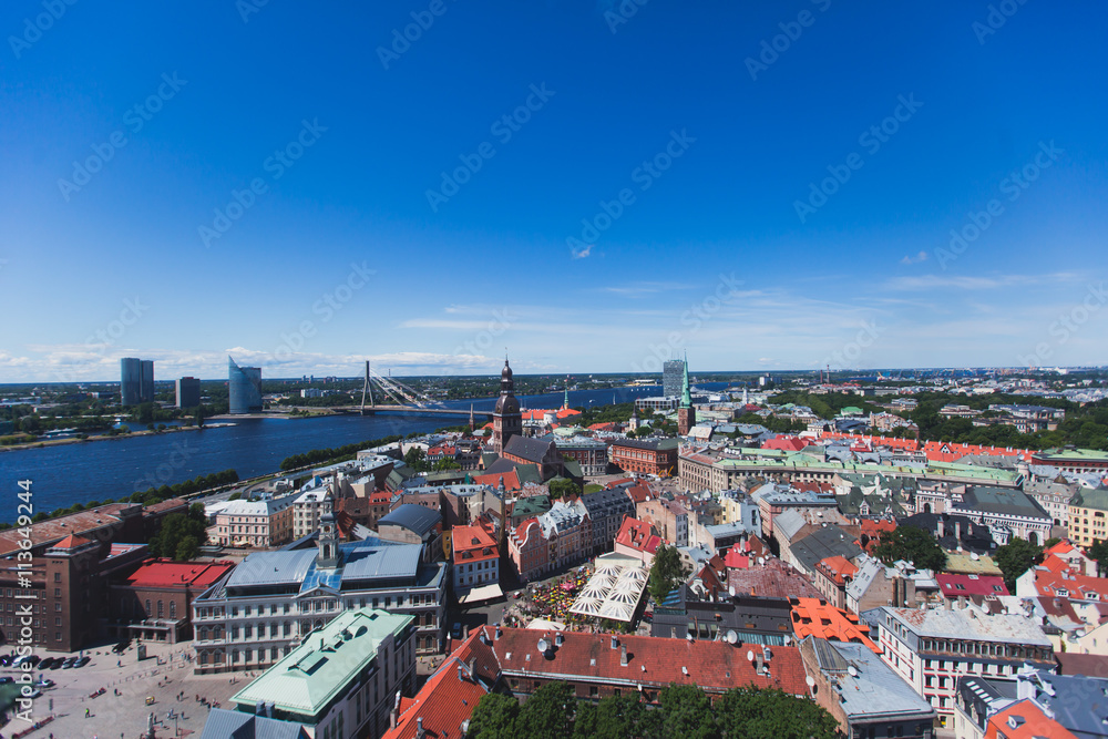 Beautiful super wide-angle panoramic aerial view of Riga, Latvia with harbor and skyline with scenery beyond the city, seen from the St. Peters Church observation tower, sunny summer day