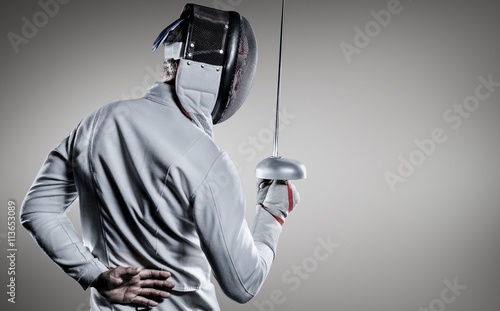Composite image of man wearing fencing suit practicing with sword Fototapeta