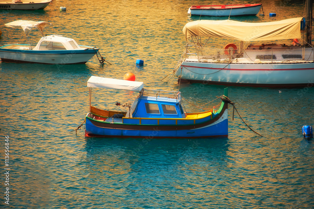 Luzzu boat moored in the harbour at sunset time. Malta