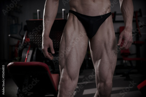 Bodybuilder posing in gym. Perfect muscular male legs