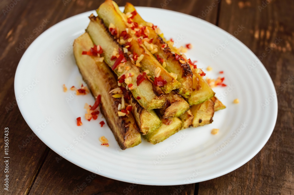 Spicy baked zucchini squash in the form of sticks with garlic and chilli. Vegan cuisine.