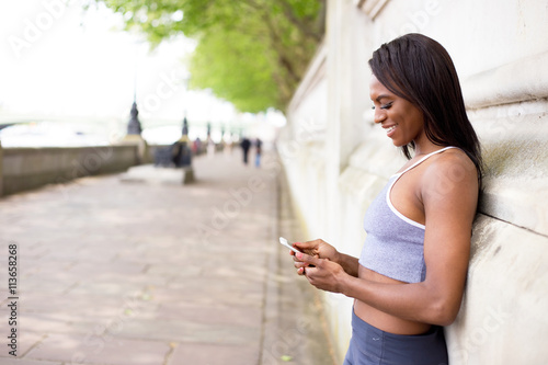 young woman checking her phone while out exercising