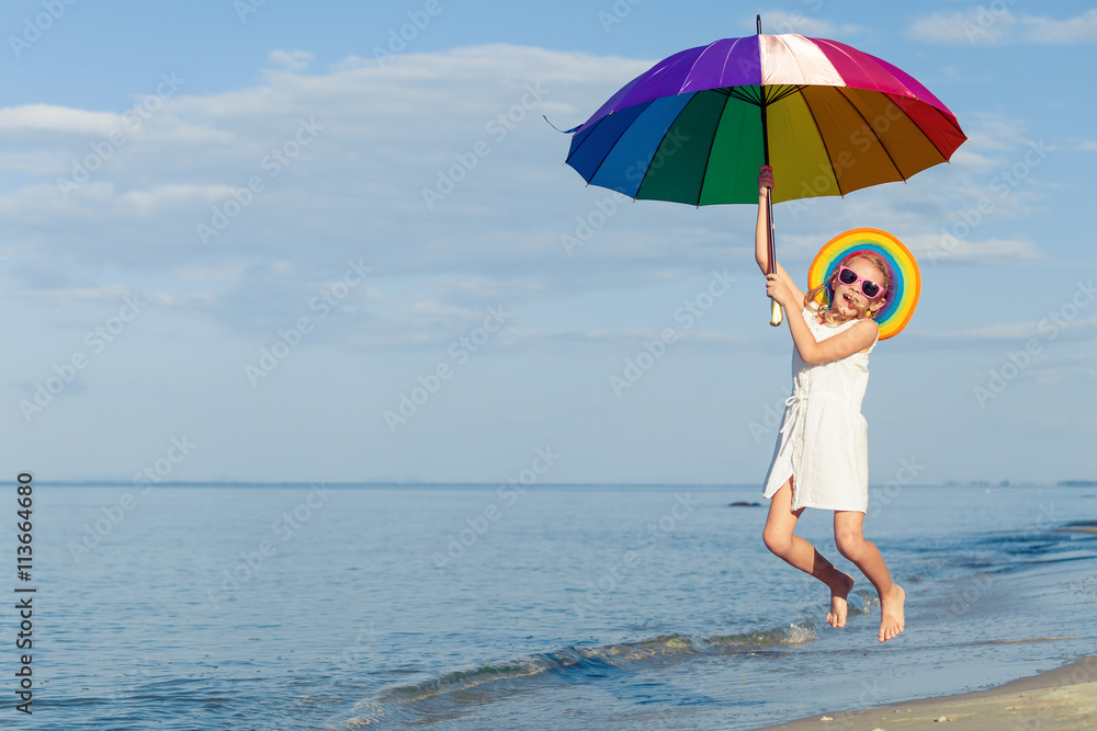 little girl with umbrella jumping on the beach