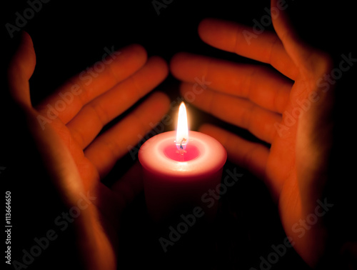 hand holding a burning candle in dark