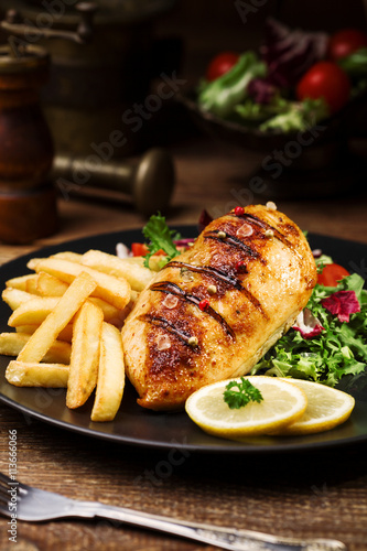grilled chicken breast with green salad and french fries.