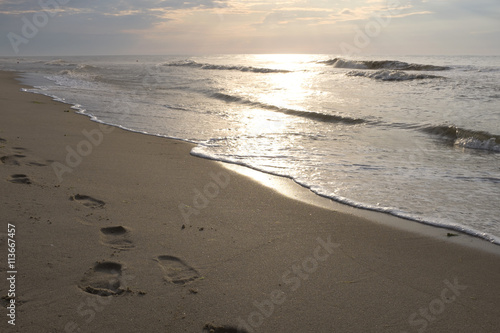 Footprints in the sand and sunset on the sea