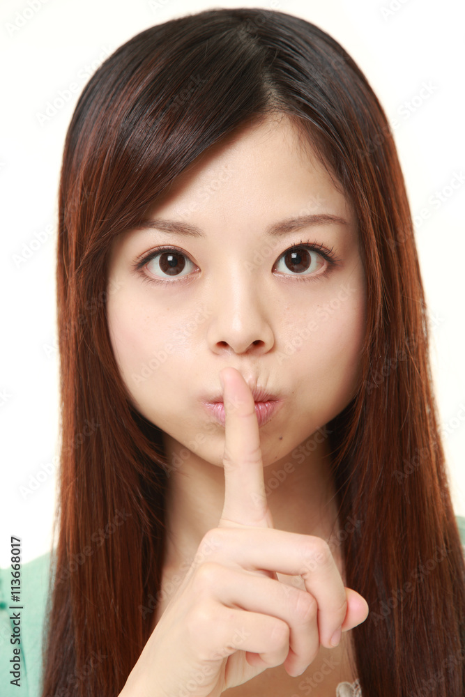 young Japanese woman wearing a green dress whith silence gestures young Japanese woman wearing a green dress whith silence gestures