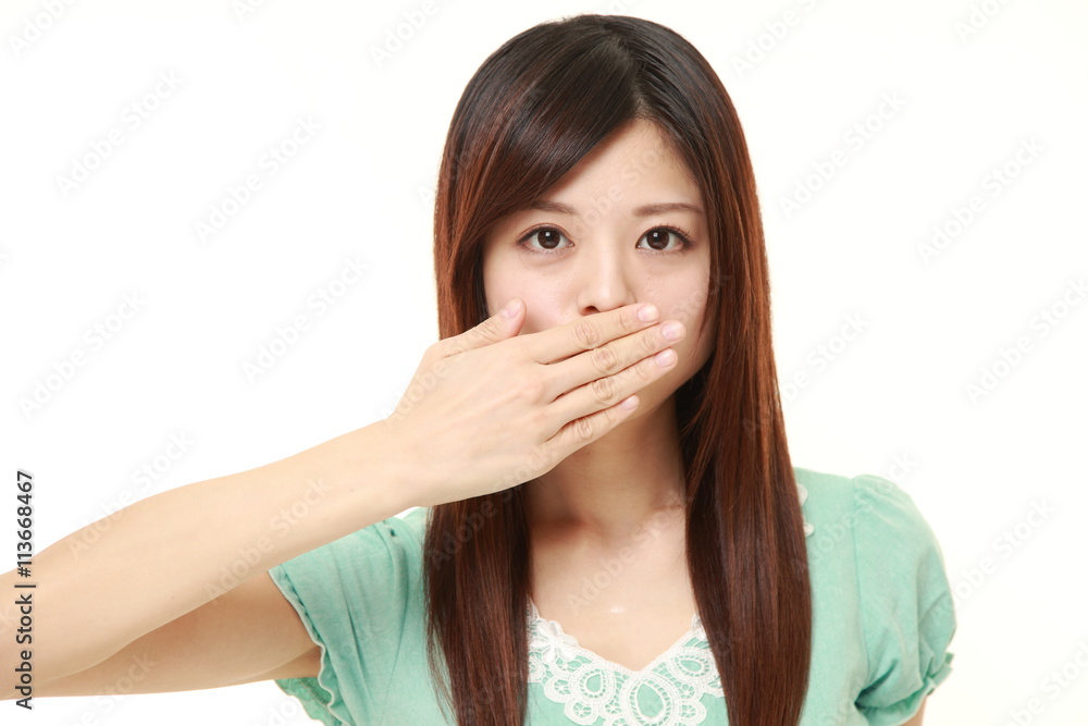 Japanese woman wearing a green summer dress making the speak no evil gesture Japanese woman wearing a green summer dress making the speak no evil gesture