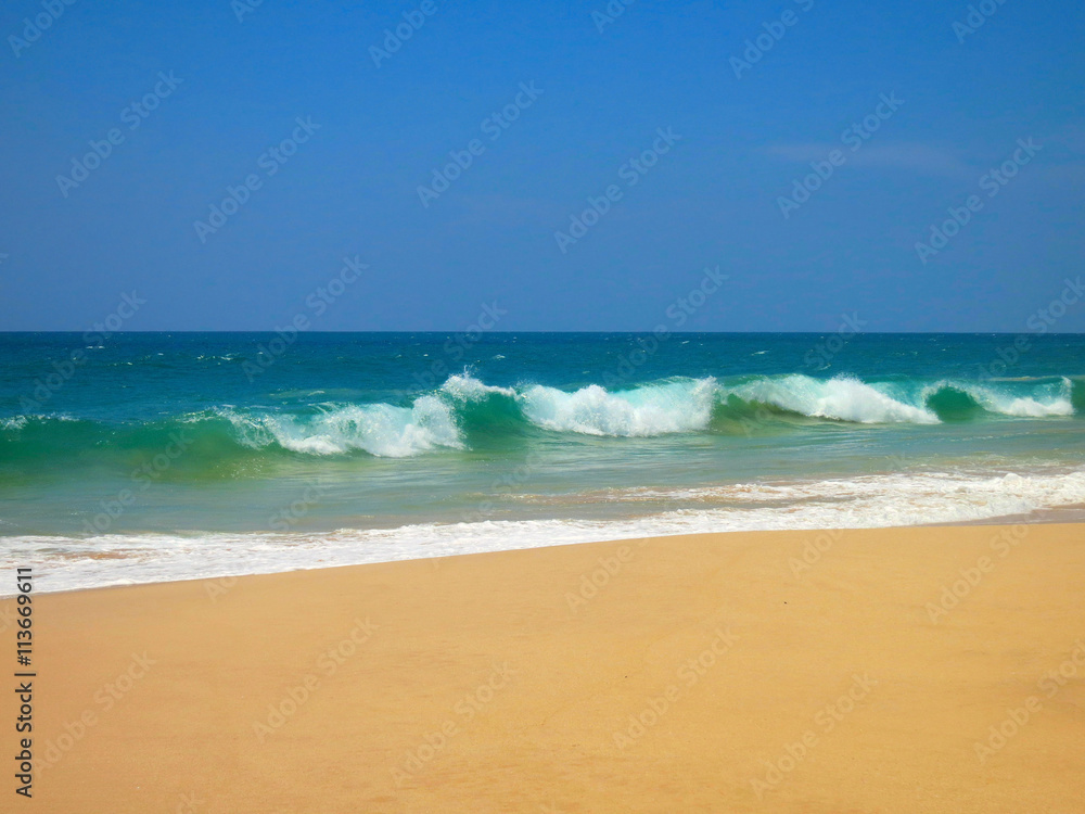 Empty ocean beach with clear sand and blue waves, Koggala, Sri Lanka