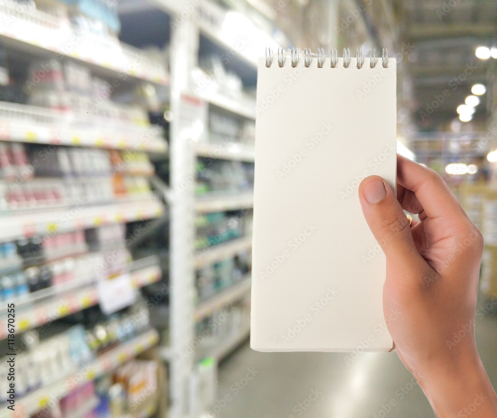Hand hold blank notepad with space for text,Supermarket blur background Hand hold blank notepad with space for text,Supermarket blur background