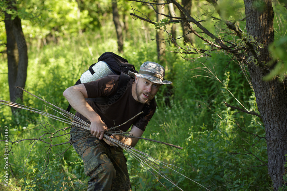 Naklejka premium Male tourist gathers dry brushwoods for the fire
