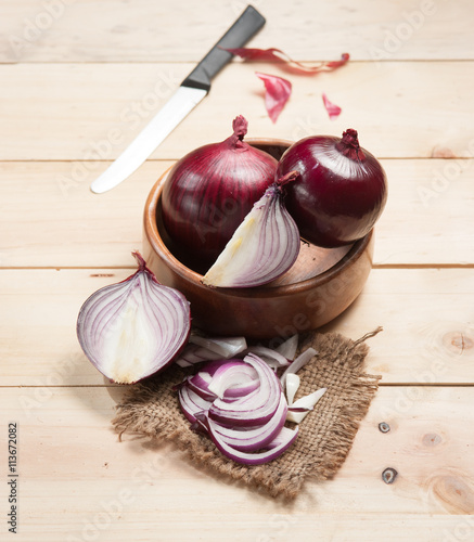 Red onion and cutting board on wooden table, selective focus