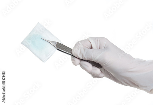 Hand with medical gloves holding tooth forceps with alcohol cott