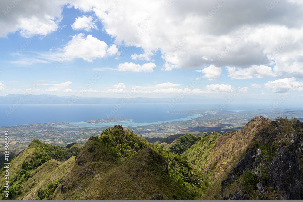 View from mountains to tropical sea under cloudy blue sky