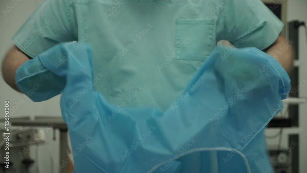 Male surgeon removes gloves and gown after surgery Male surgeon removes gloves and gown after surgery