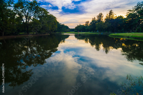 Fototapeta Naklejka Na Ścianę i Meble -  Public park with pond sunset beautiful sky in evening