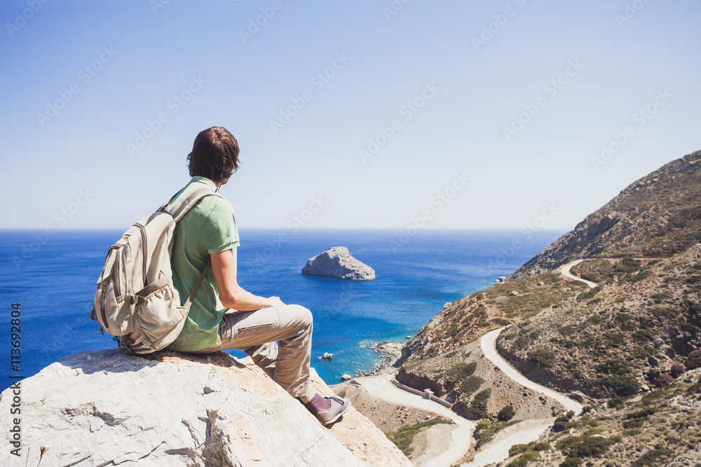 Young man traveler looking at the sea, travel and active lifestyle concept