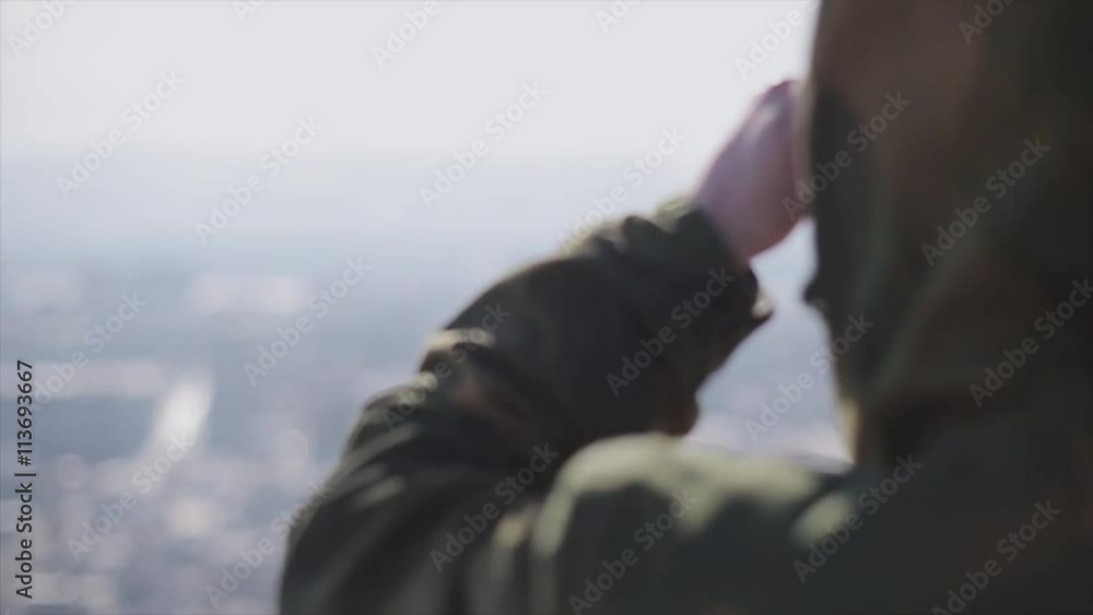 Back side of man, covers eyes from sun look around at viewing platform. Sunny day. Cold shades. Military jacket. Slow motion Back side of man, covers eyes from sun look around at viewing platform. Sunny day. Cold shades. Military jacket. Slow motion