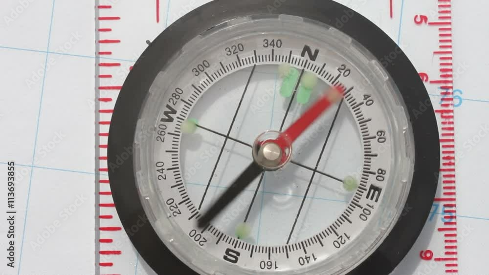Close up of a magnetic directional compass with a needle pointer spinning round in all directions and ends pointing South. Close up of a magnetic directional compass with a needle pointer spinning round in all directions and ends pointing South.