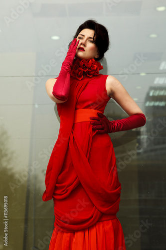 Beautiful woman in red dress on the background of a large window