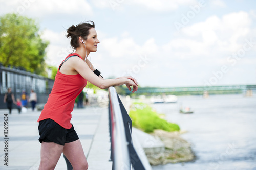 Fit woman jogger resting after run listening music. © Wisiel