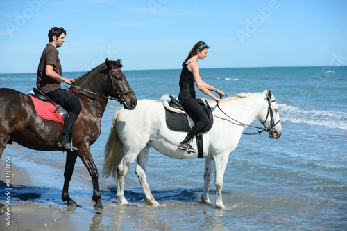 happy young couple vacation riding horses on the beach in sunny summer day © W PRODUCTION