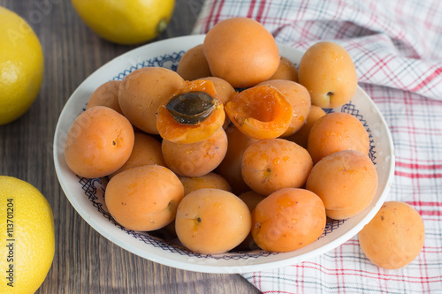 Fresh organic apricots in glass bowl on wooden board