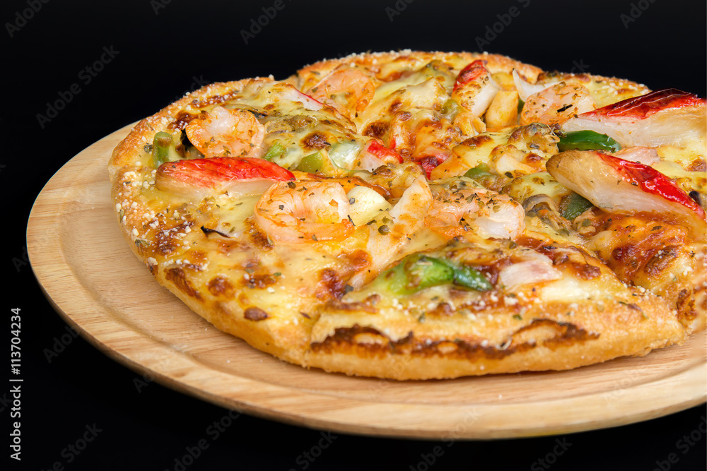 Seafood pizza on a wooden tray.