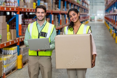 Happy workers are holding laptop and cardboard box and posing