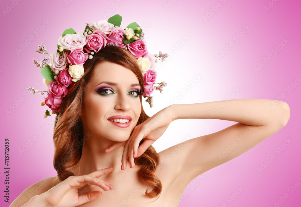 Beautiful young woman wearing floral headband on pink background