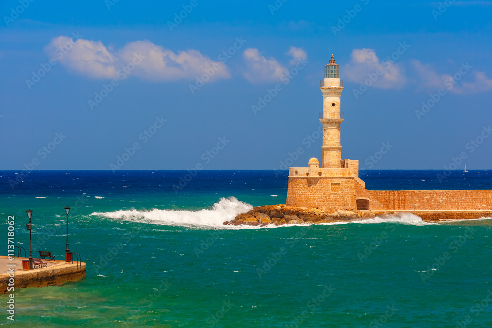 Waves beat against the lighthouse in old harbour of Chania in the summer sunny day, Crete, Greece