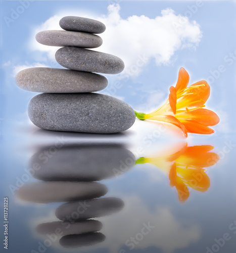 Spa stones with flower on sky background