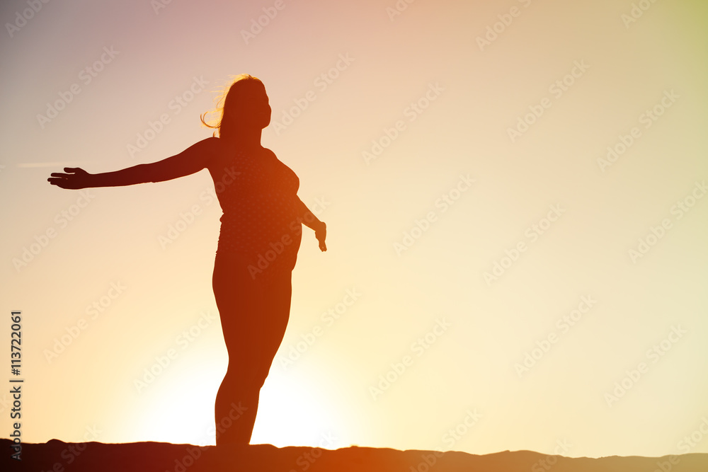 Silhouette of happy pregnant woman at sunset