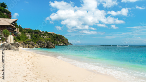 Fototapeta Naklejka Na Ścianę i Meble -  Beautiful tropical beach at midday with small waves breaking on the shoreline and a rocky headland in the distance.