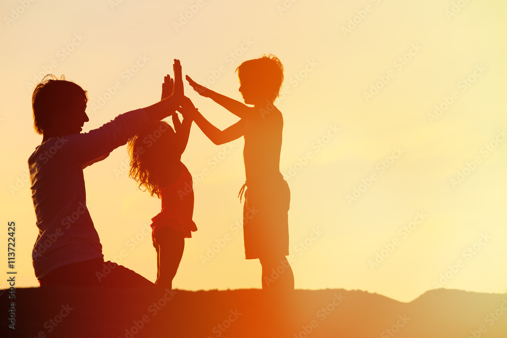 father with son and daughter silhouettes play at sunset father with son and daughter silhouettes play at sunset