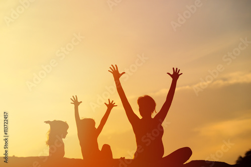 Silhouette of happy mother and kids at sunset