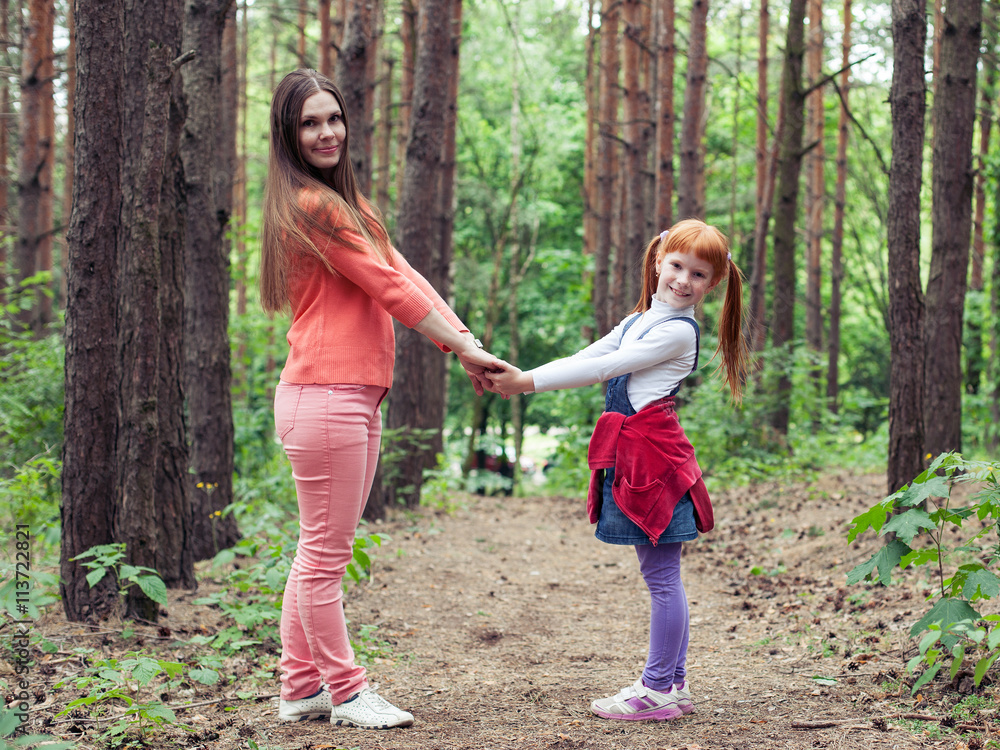 Mother and daughter holding hands and smiling in the woods Mother and daughter holding hands and smiling in the woods