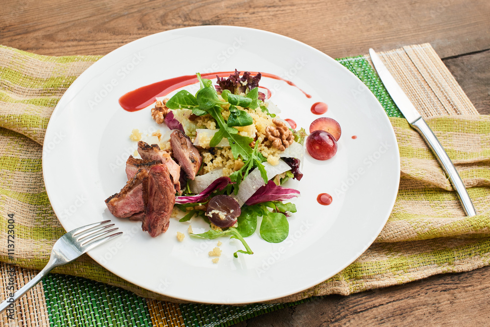 A healthy Breakfast consisting of a salad with duck breast, daikon, grapes and couscous served on a white plate A healthy Breakfast consisting of a salad with duck breast, daikon, grapes and couscous served on a white plate