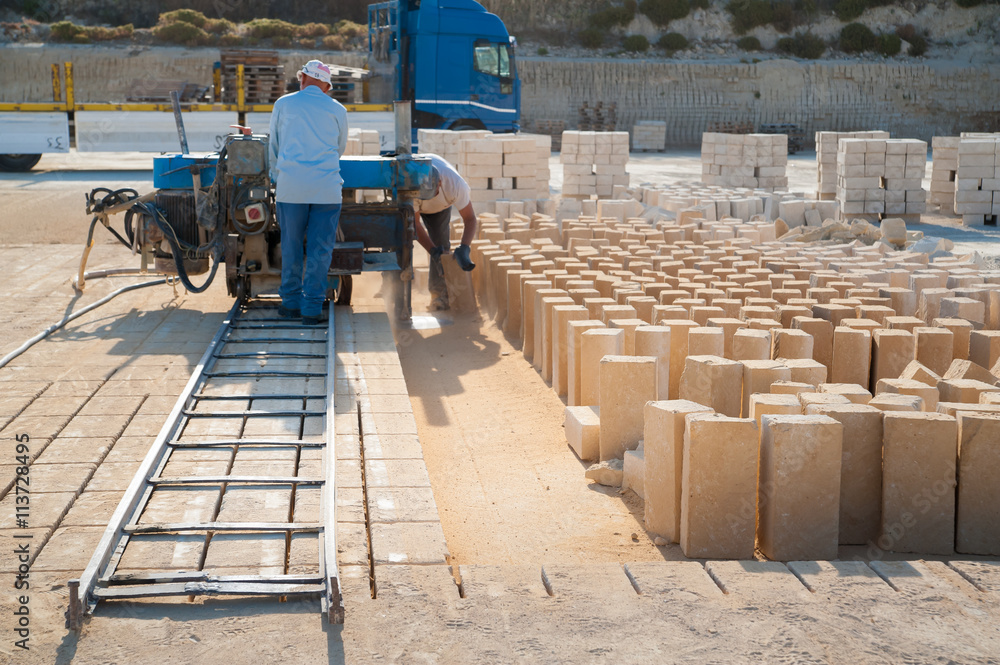 Workers using an horizontal sawing machine on a platform and just cut tufa blocks in a quarry