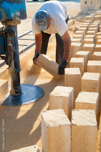 Obraz na płótnie Just cut tufa blocks while a worker is using a sawing machine to cut the stone horizontally w salonie