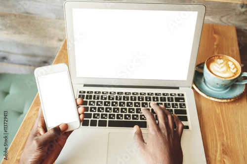 People and technology concept. Close up portrait of African American using mobile phone, paying for online purchase via mobile banking while shopping on the Internet, using Wi-Fi at a coffee shop