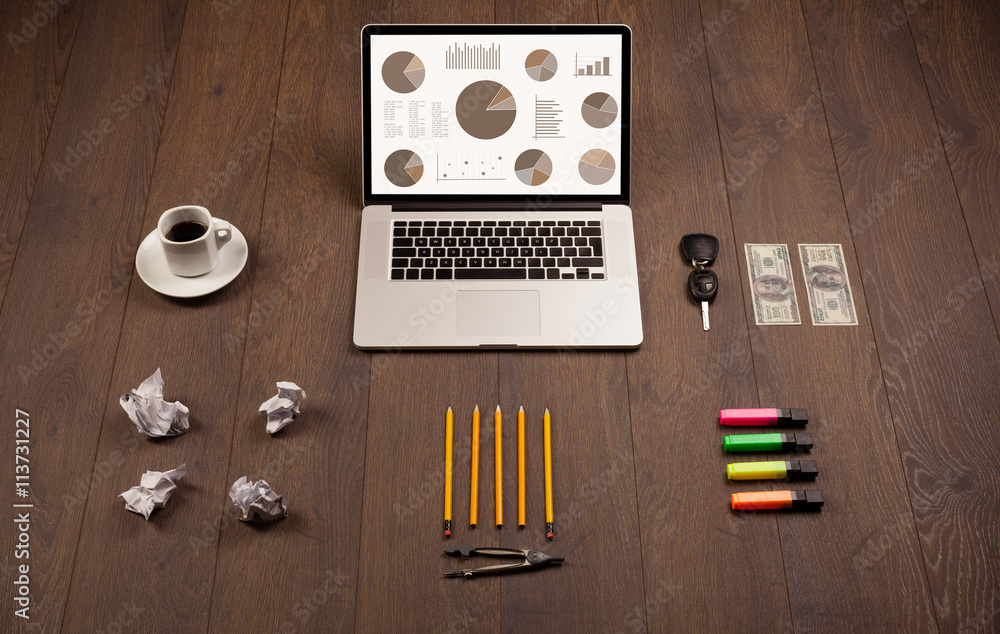 Pie chart graph icons on laptop screen with office accessories Pie chart graph icons on laptop screen with office accessories