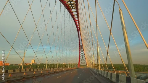 NOVOSIBIRSK, RUSSIA - JUNE 18, 2016: Driving along arched combined joist suspended Bugrinsky bridge over river Ob in Novosibirsk at early morning . photo