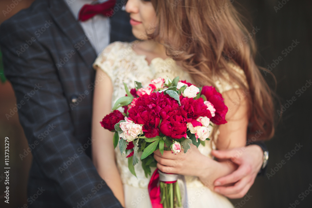 Wedding couple hugging, the bride holding a bouquet of flowers in her hand, groom embracing Wedding couple hugging, the bride holding a bouquet of flowers in her hand, groom embracing