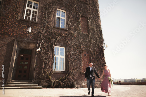 Young wedding couple in love story, bride and groom posing near building on the background. Krakow