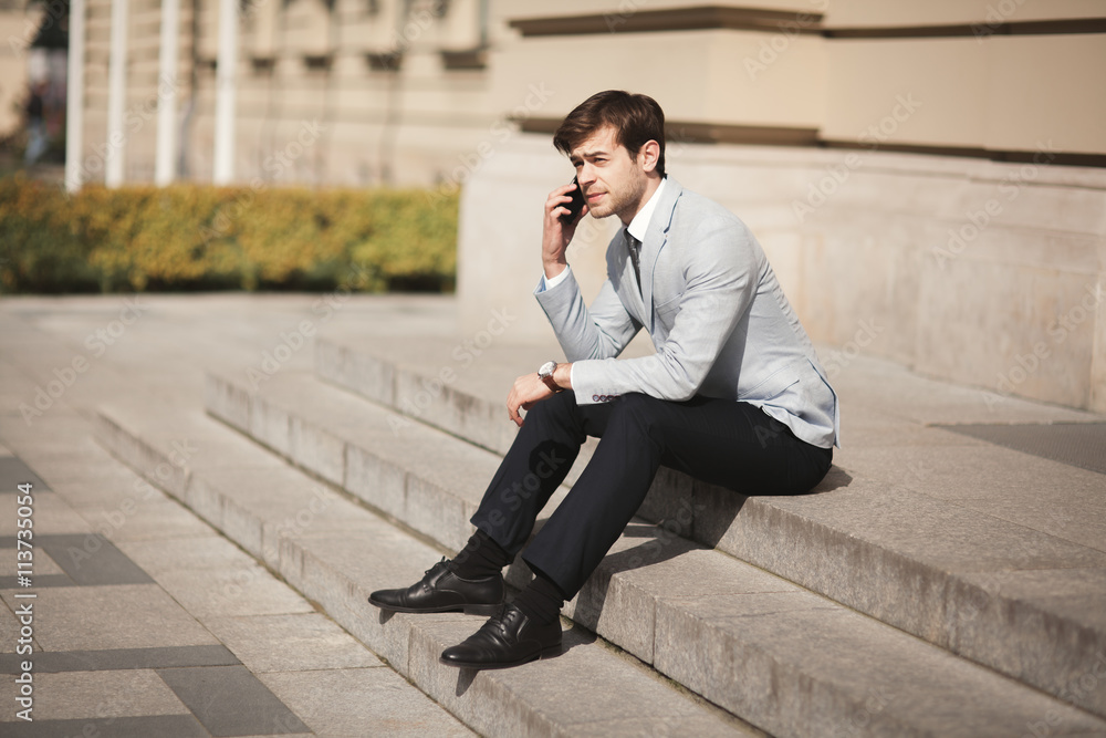 Stylish young businessman talking on the phone outdoors